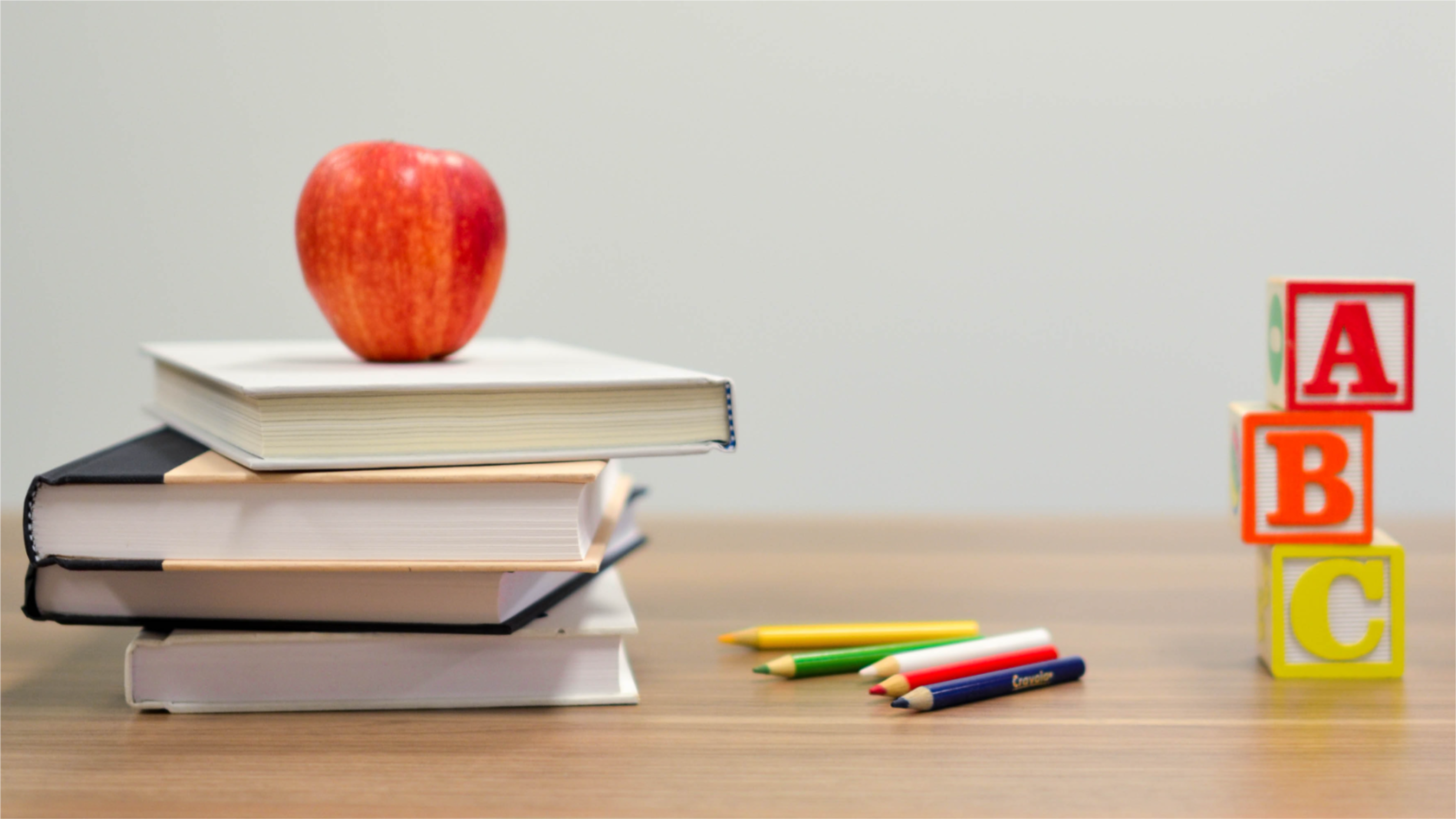 Class image, apple on books, colored pencils, ABC blocks