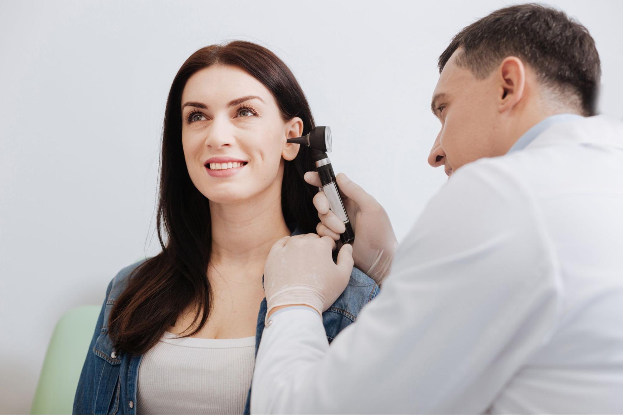ear crackling: doctor examining the ear of a woman