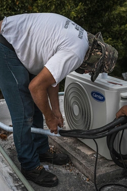 A photo of an HVAC technician installing an outdoor AC.