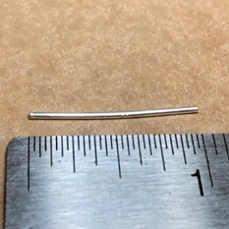 a piece of silver wire approximately 1 inch long next to a ruler