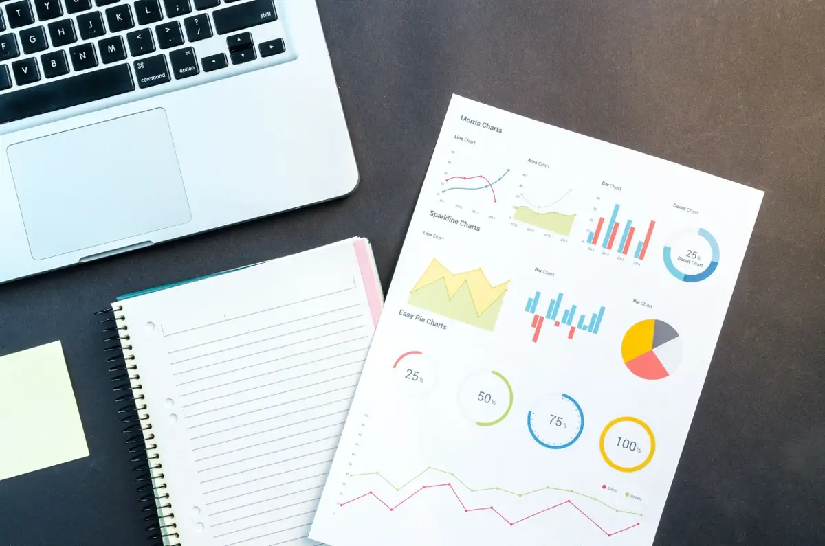 Sales analytics document on a table with a laptop and notebook.