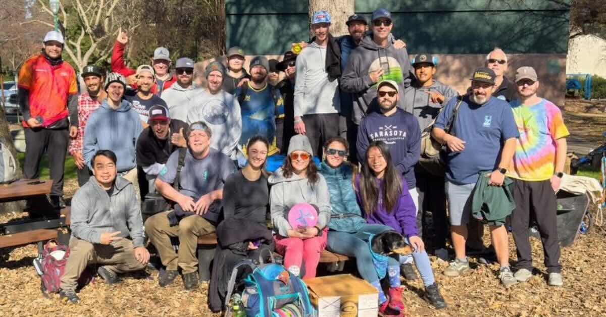 a large group of disc golfers pose for a photo