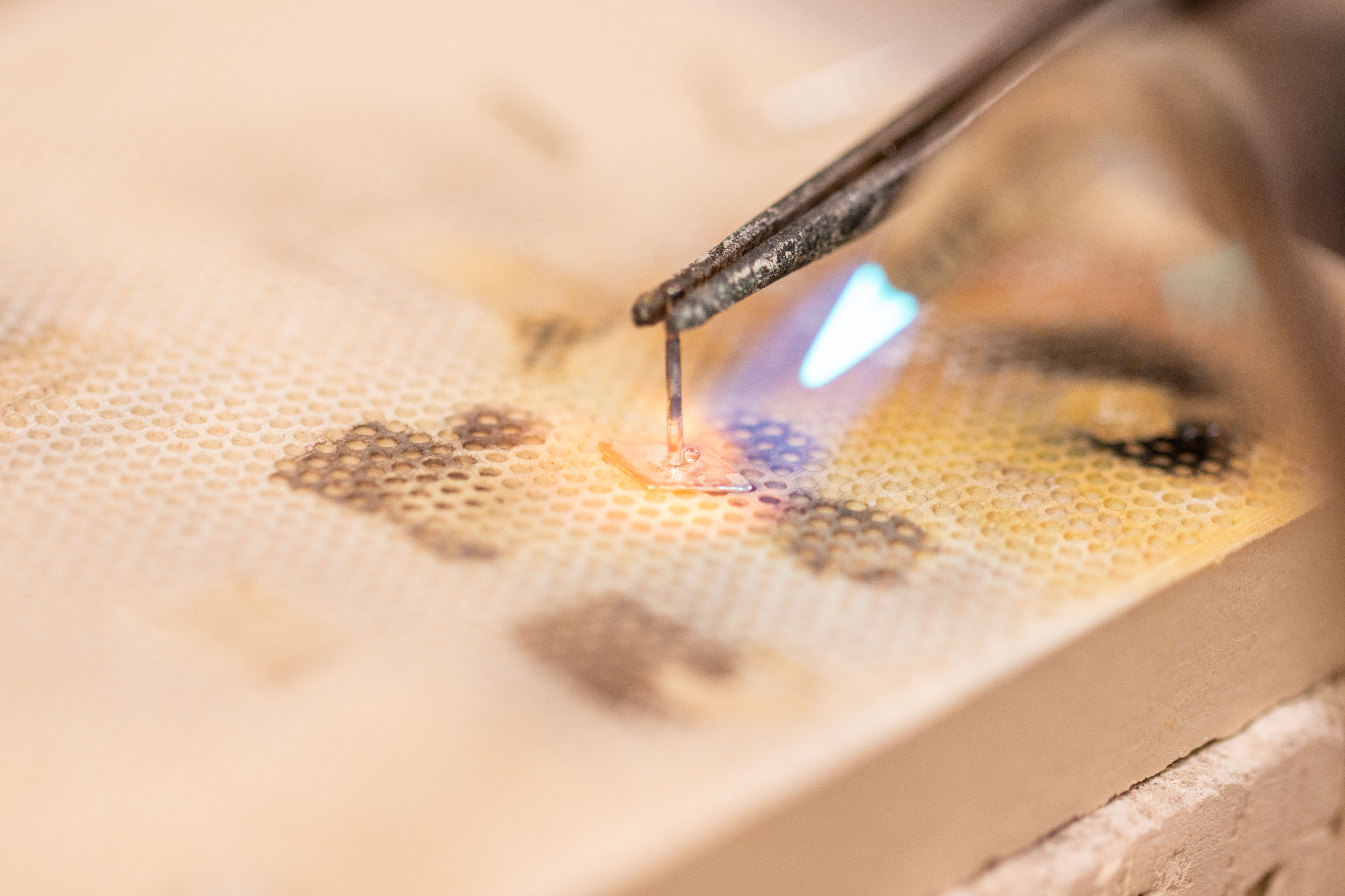 Earring post being soldered to diamond shape with torch