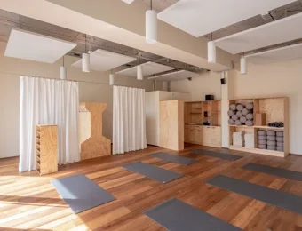 Yoga-Studio mit Blick auf den Garderobenbereich, offene Raumstruktur mit klar erkennbaren Zugängen zu Umkleide- und Ablageflächen.