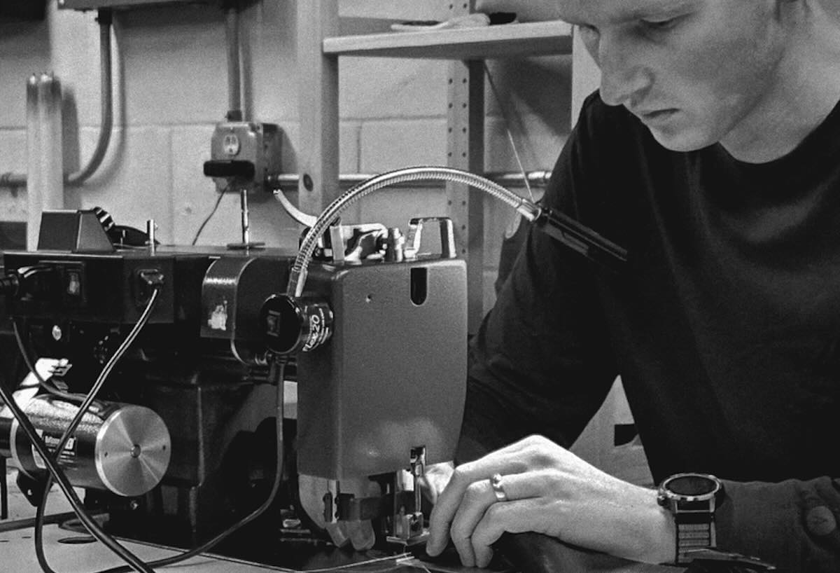 A black and white photo of a man working at a sowing machine