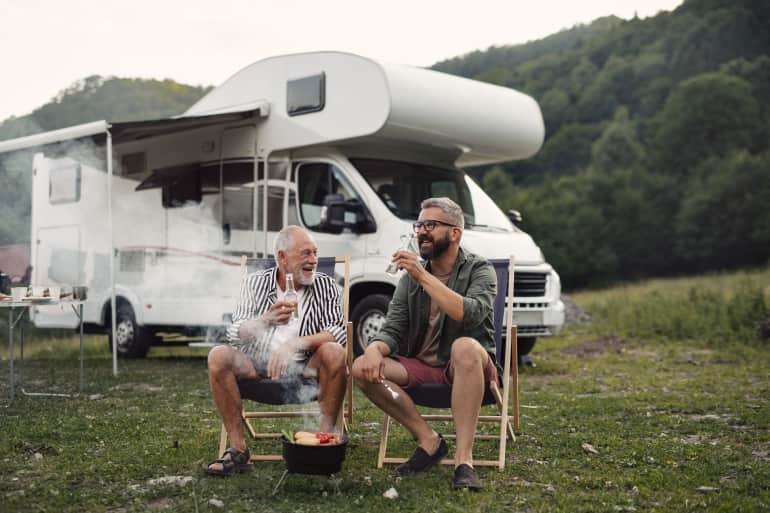 older father and son hanging in from of camper having a beer