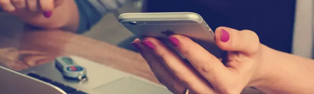 hands holding a phone above a laptop keyboard