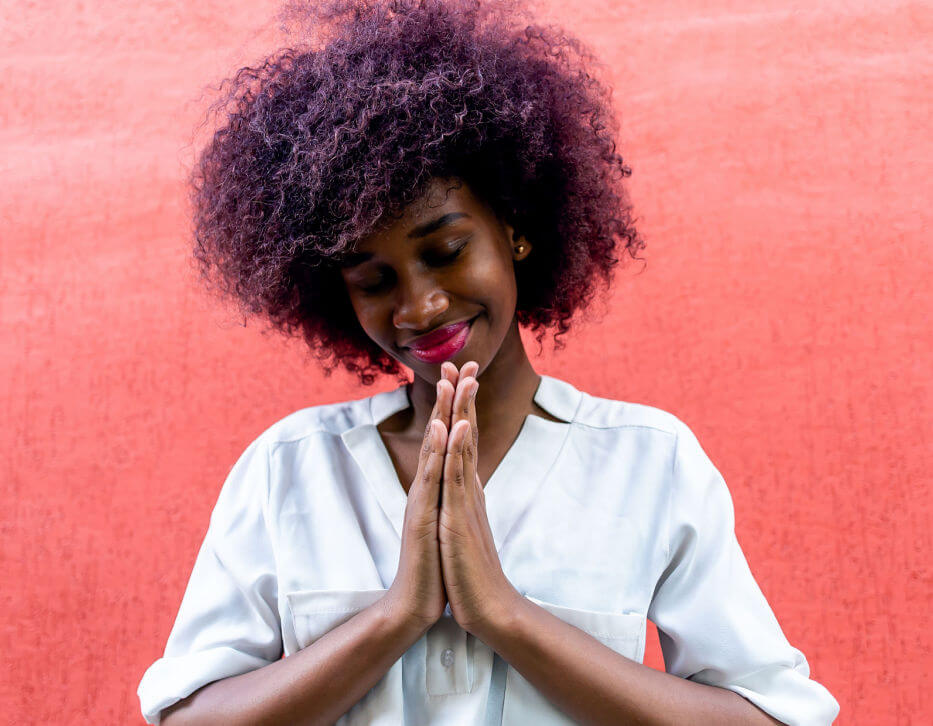 a black woman clasps her hands in prayer and shows how to practice gratitude
