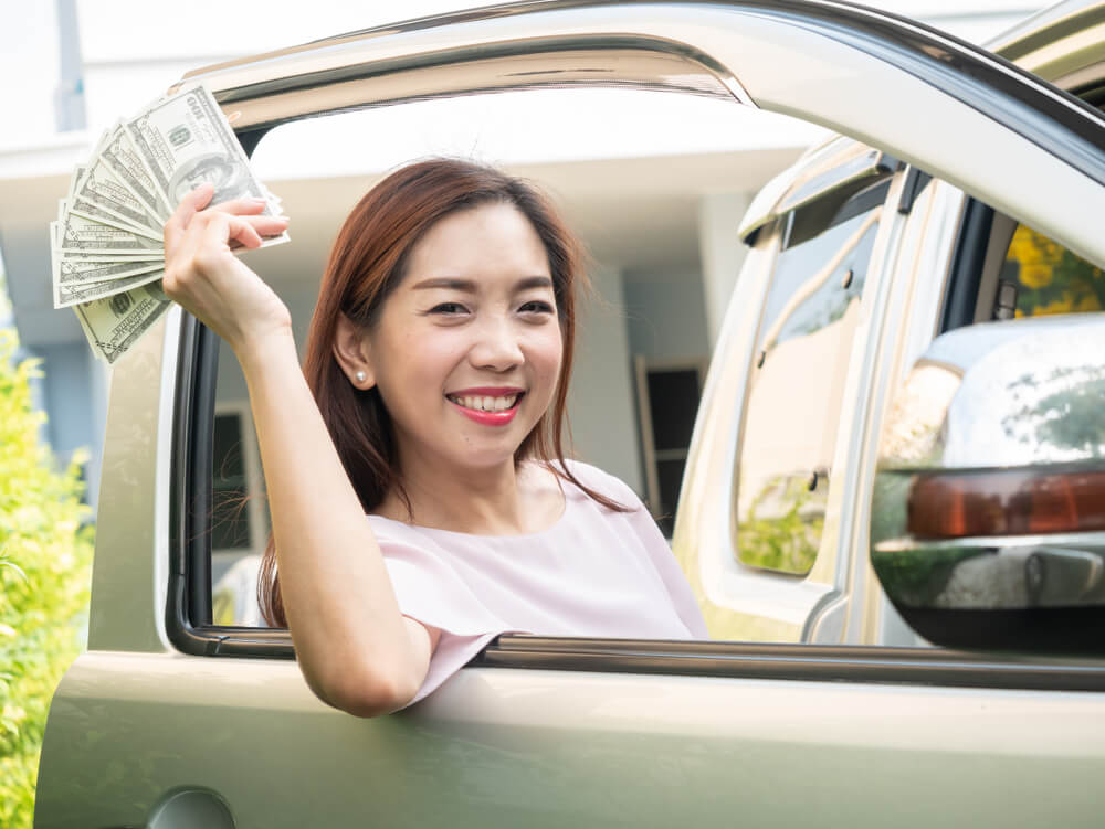 woman holding title loan next to the car