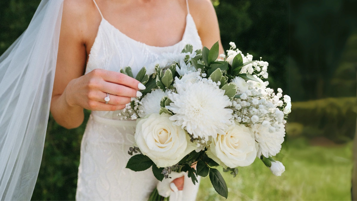 Neutral bridal bouquet with white roses, baby's breath and ruscus greenery.