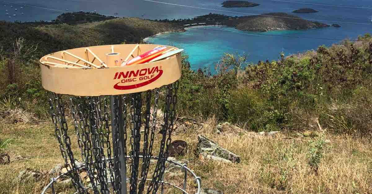 Top of a disc golf basket in foreground with turquoise sea in the background