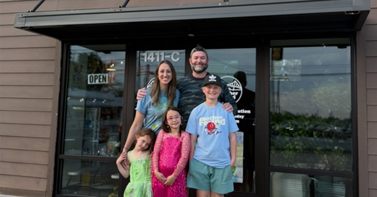 Family with mom, dad, three kids posed in front of a store entrance