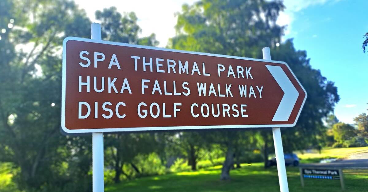 A sign pointing to attractions in a park, including disc golf