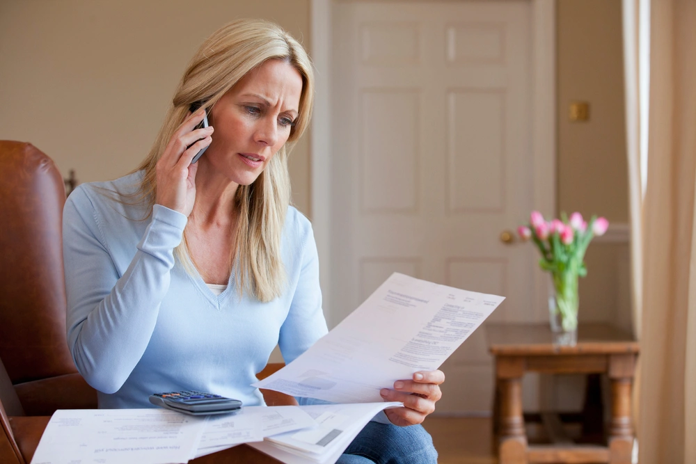 concerned woman looking at bills and talking on her mobile