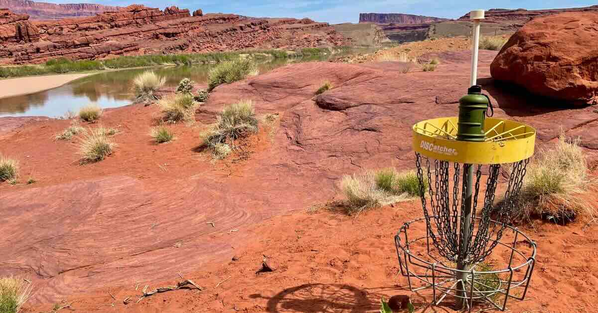 A yellow-banded disc golf basket in a stunning red rock desert
