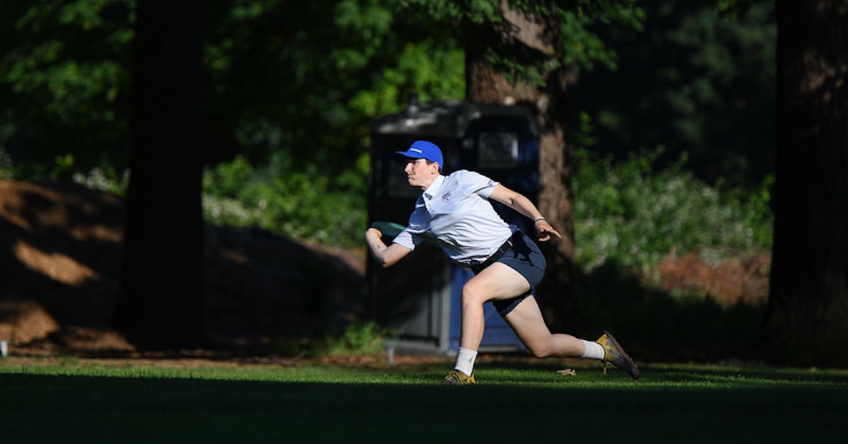 A woman throws a forehand on a disc golf course