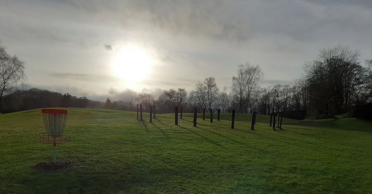 sun shines through clouds on a basket in a green field