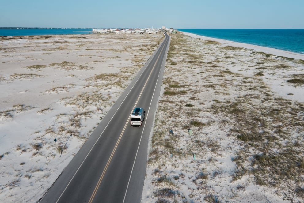 aerial shot of winnebago solis rv driving on beach road in florida