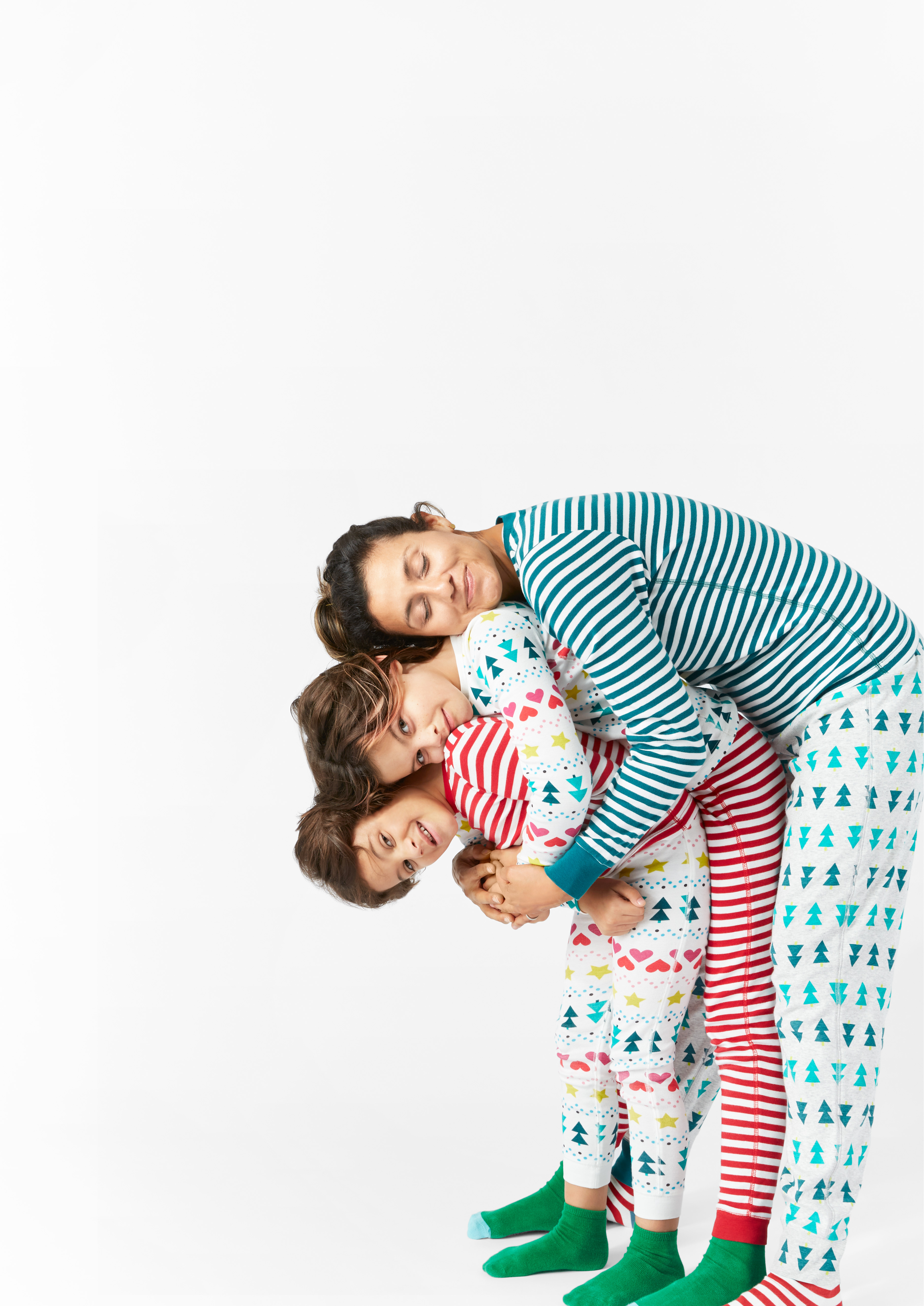 mom and kids hugging each other in mix-and-match holiday pajamas