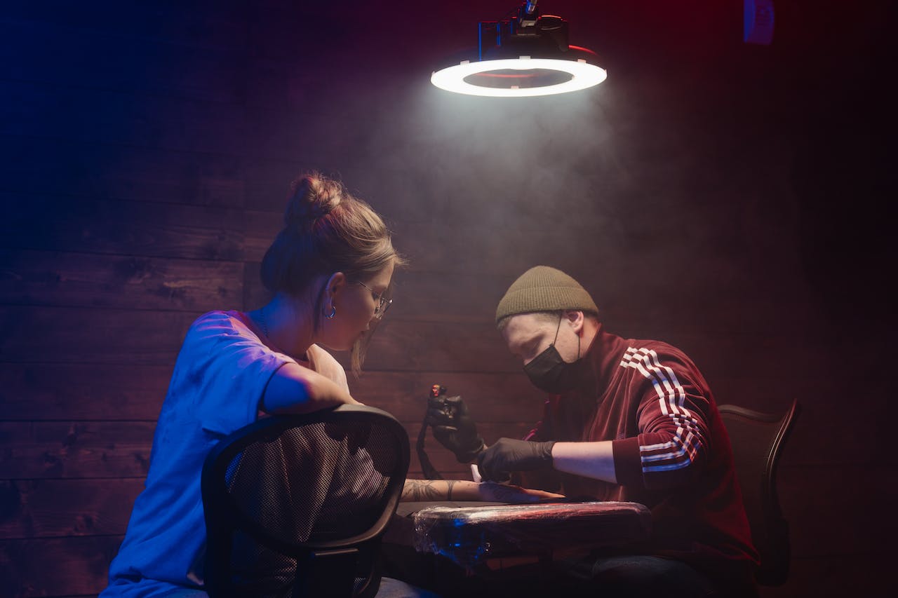 tattoo artist and client under hazy light