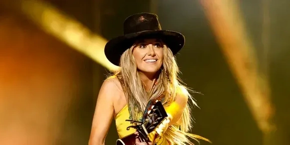 Lainey Wilson on stage, playing a guitar.