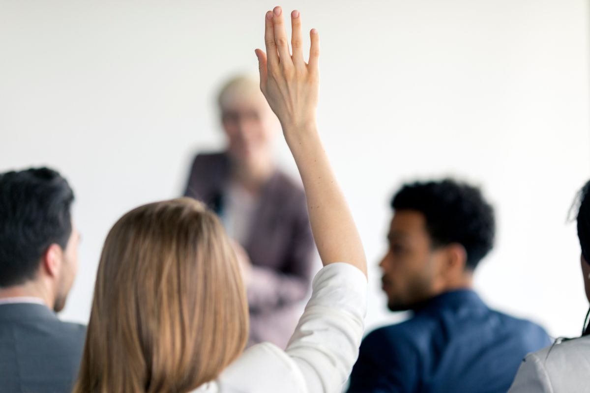 Woman with raised hand, asking if she should sign up for Medicare Part B