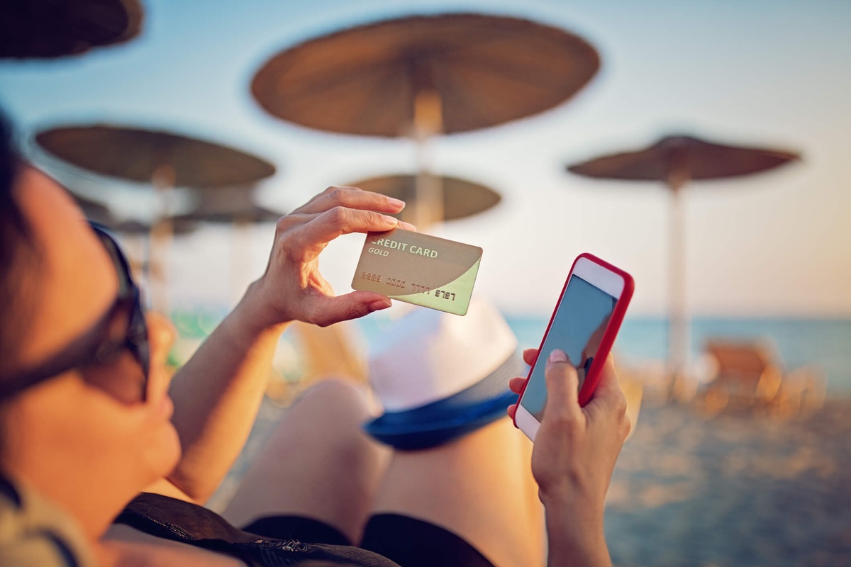 Lady on a beach with a credit card in hand