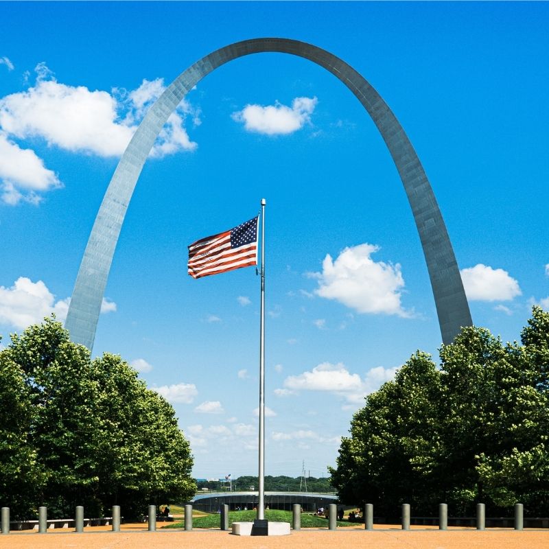 The Gateway Arch with the American flag in front of it