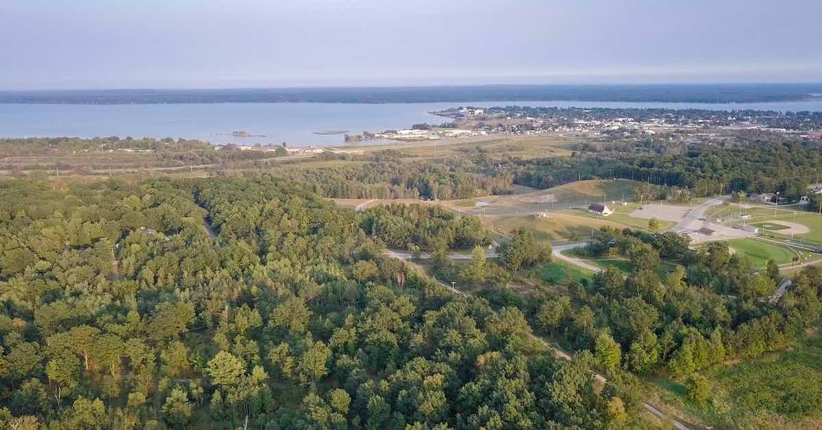 Aerial view of a wooded area near a body of water and small community