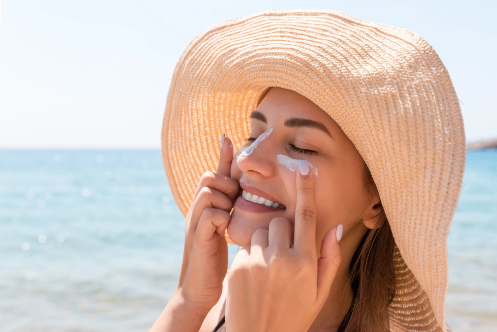 Woman applying sunscreen to her cheeks