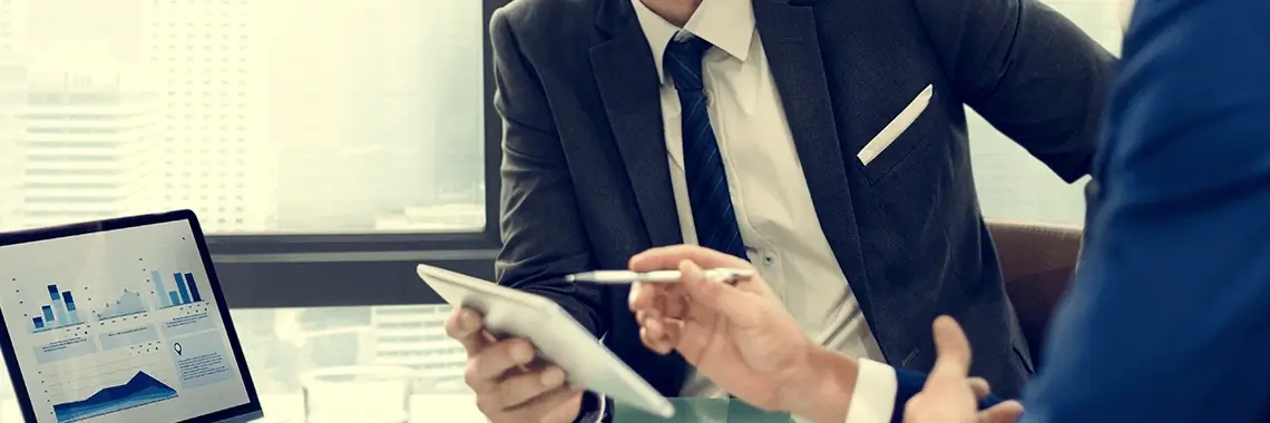 A sales manager showing a rep metrics on a laptop.