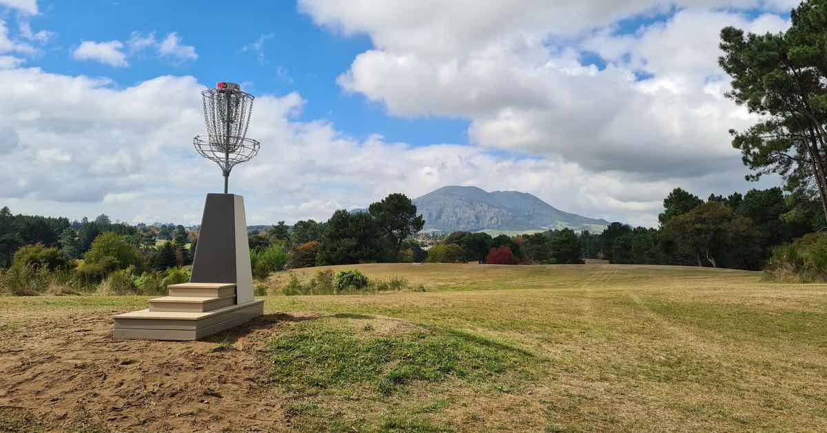 An elevated basket in a field with a mountain in the background