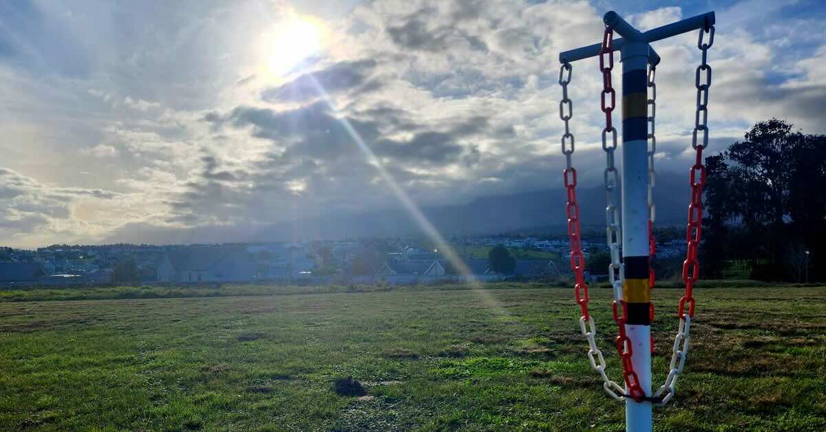 A straight plastic pole with plastic chain links dangling from an x-shaped cross at its top