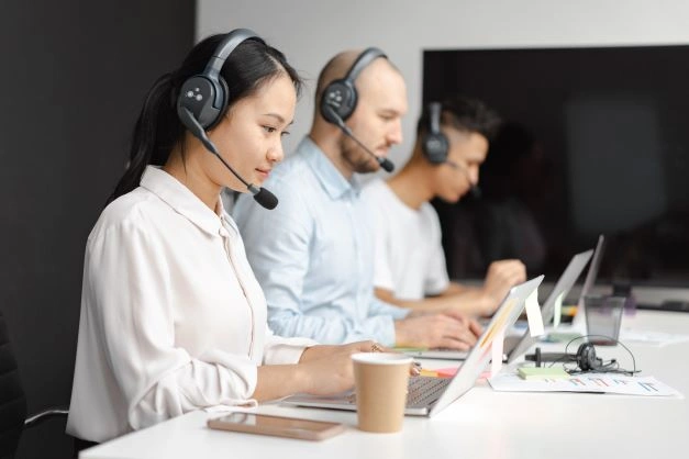 A group of sales reps communicating with their clients using headphones while experiencing the benefits of CRM for sales.