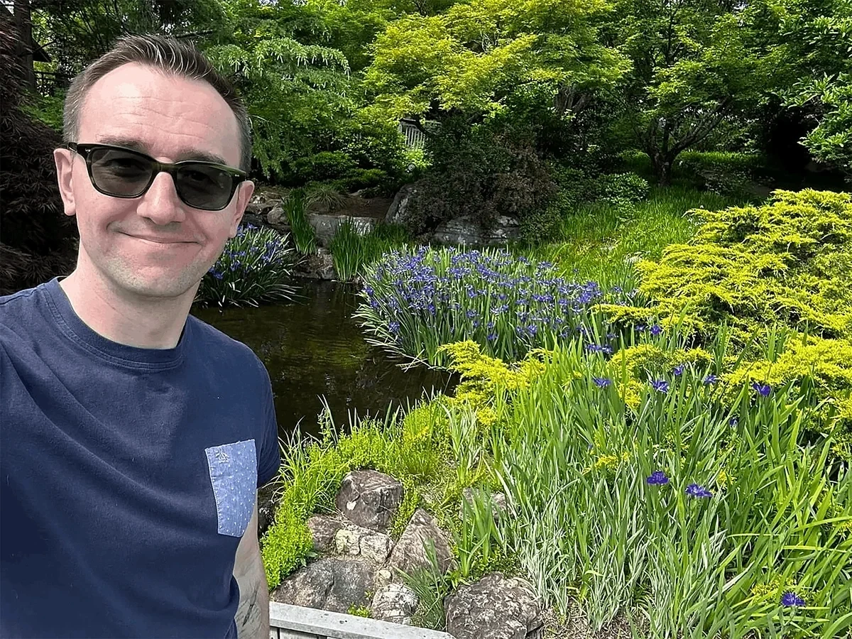 Travel blogger Christopher Mitchell poses in a botanical garden in Virginia, USA.