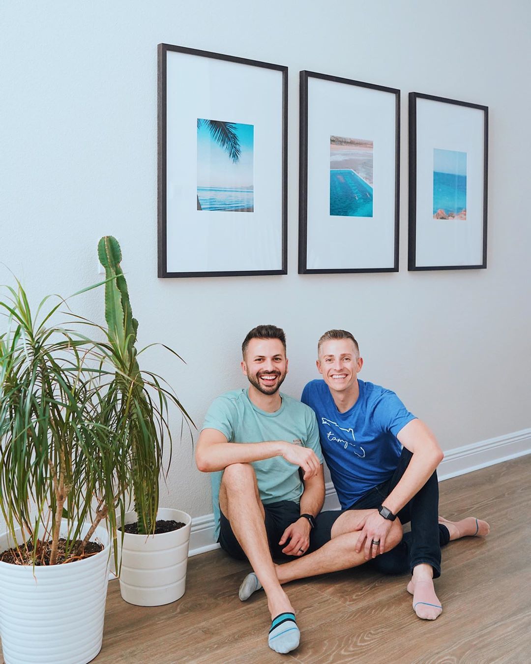 triptych gallery in hallway with two smiling men and a plant
