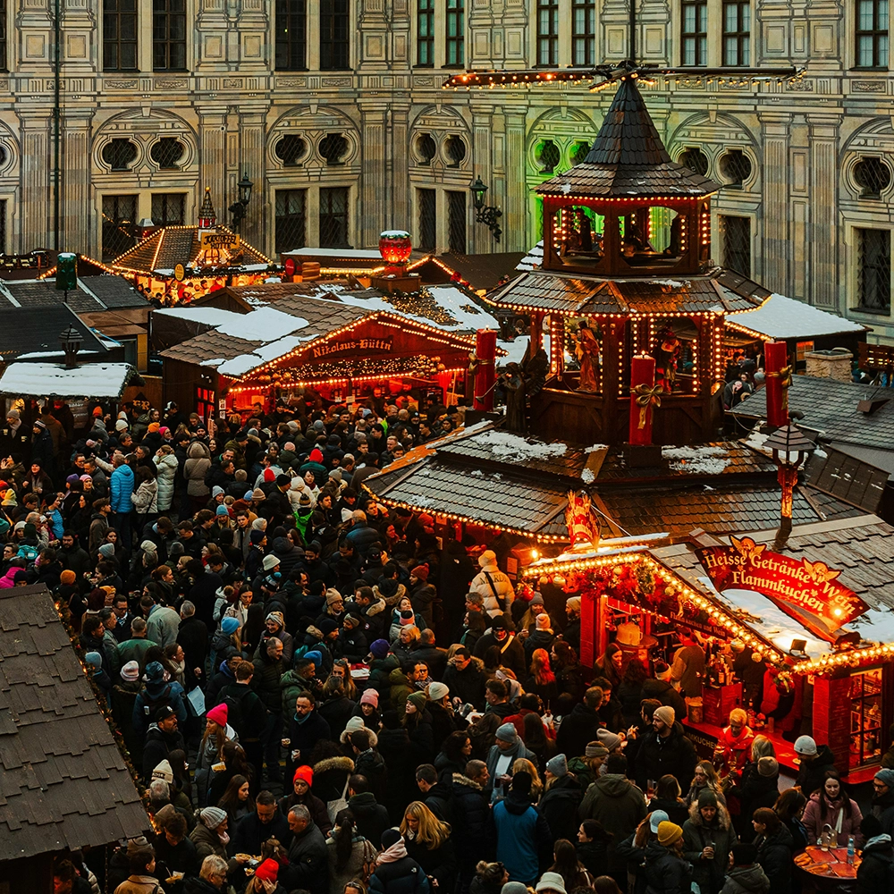 A crowd of people standing around a christmas market in Munich.