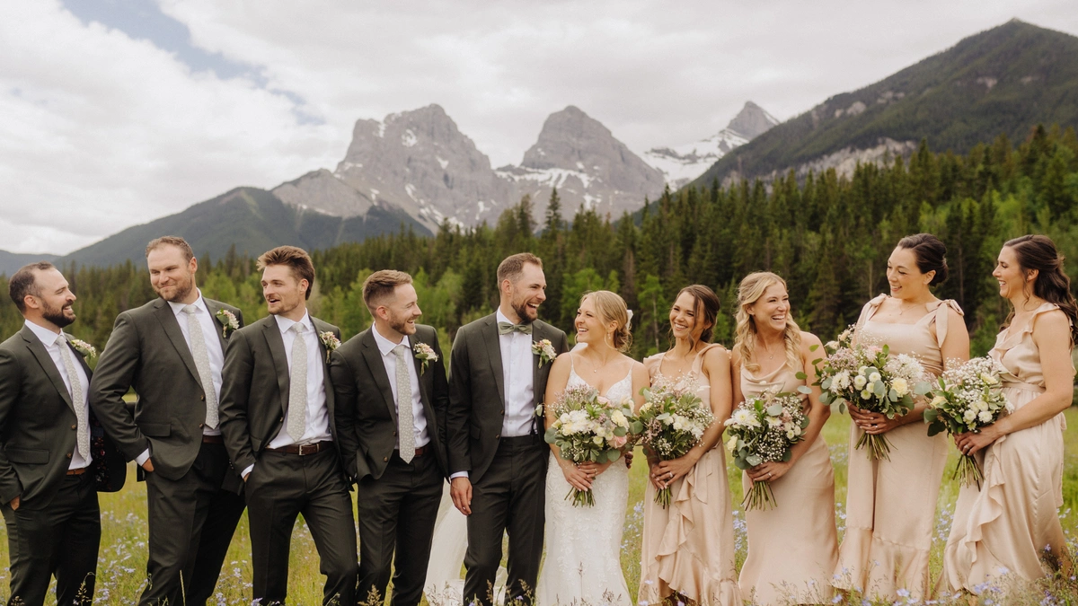 Happy bride and groom in the middle of their wedding party who's all smiling and laughing.