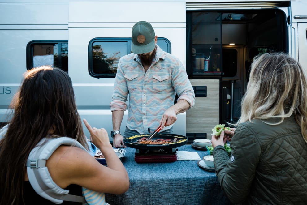 man cooking for family outside of winnebago solis rv