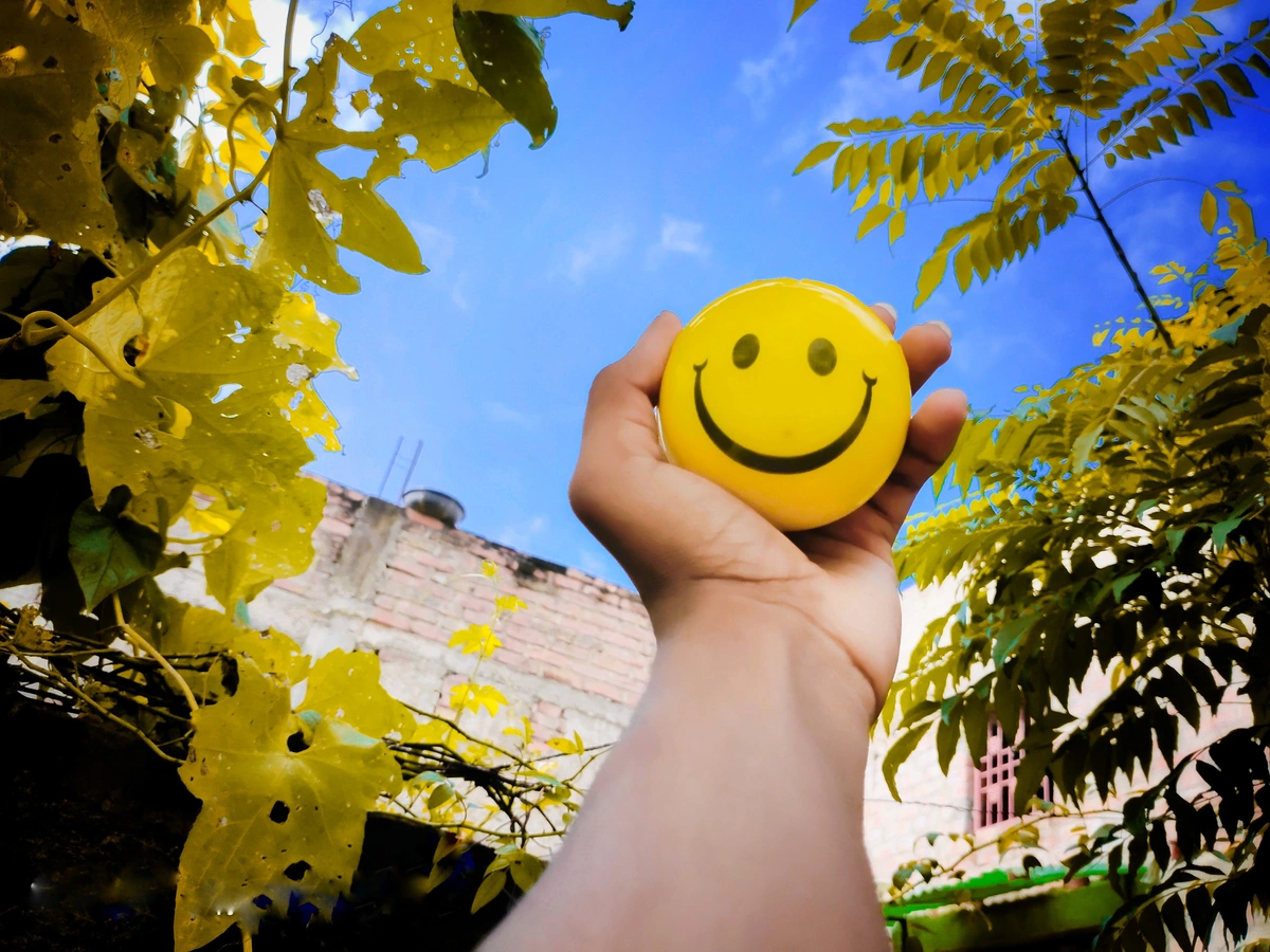 A person holds a ball with a smiley face on it, symbolizing a happy customer. Learn about tracking customer satisfaction.