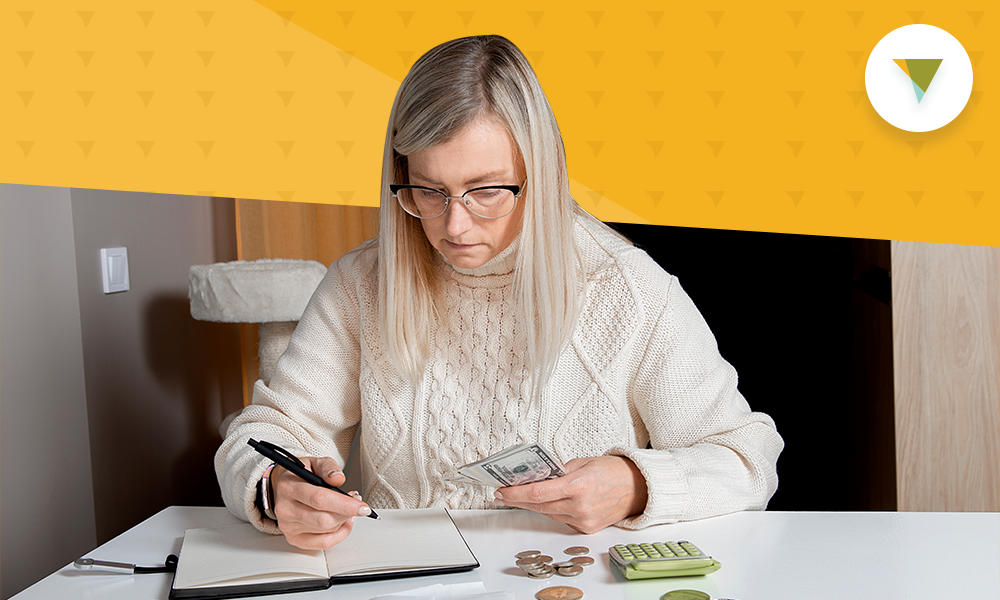 Woman counting money and writing in notebook.