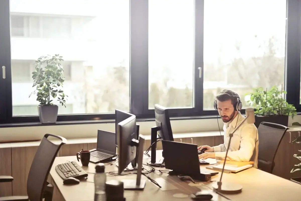 Man in office using inbound call center software to handle a customer inquiry at his computer.