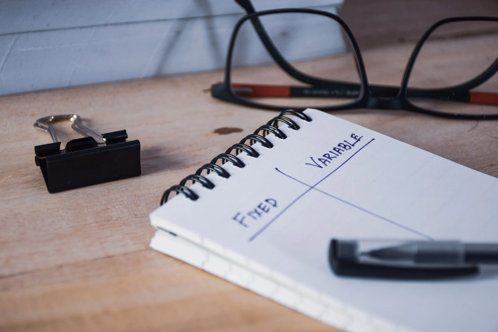 A notepad with the words fixed and variable written in two separate columns