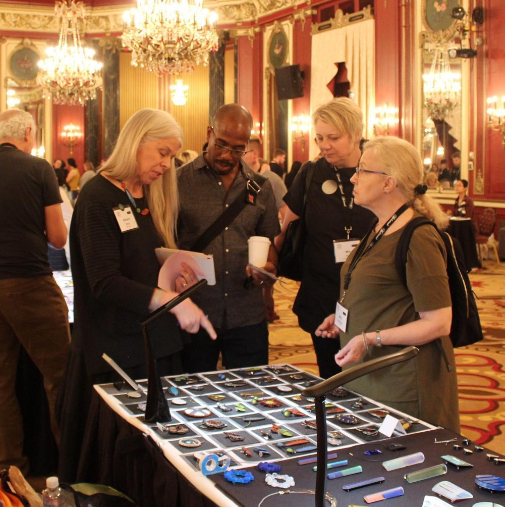 people conversing around a table with jewelry on display