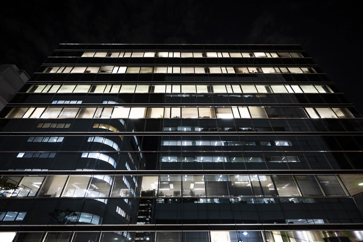  tall office building with multiple floors illuminated from within, showcasing a modern architectural design against a dark night sky.