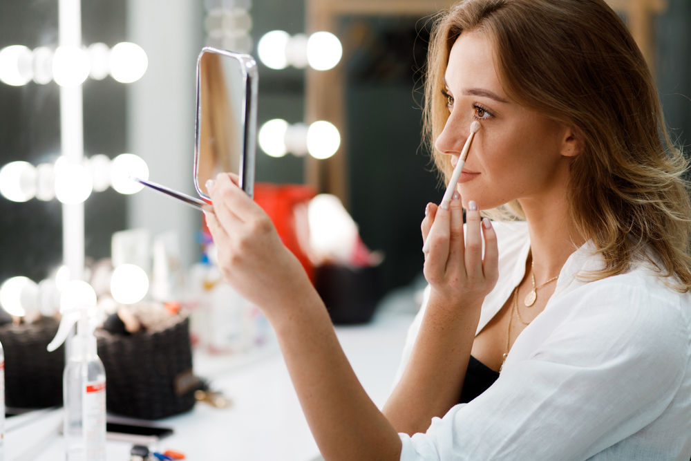 Woman doing her makeup in the mirror