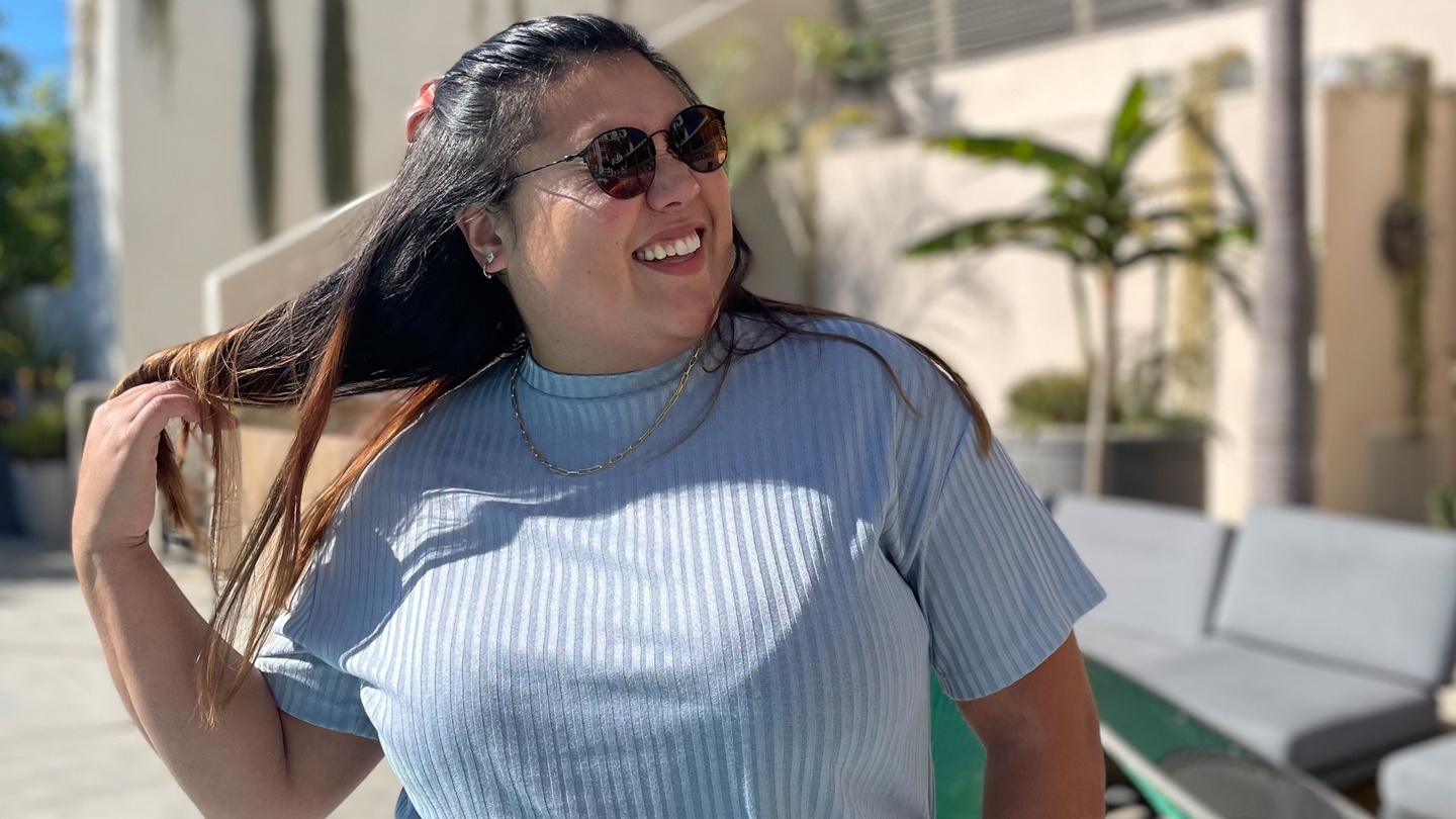 a fat brown femme in sunglasses with a blue top living her best life