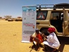 A person administering an injection to another in front of a truck 