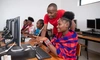 Two young people working together on a computer at a desk, 5 x 3.