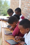 Students sitting at a desk looking at tablets 